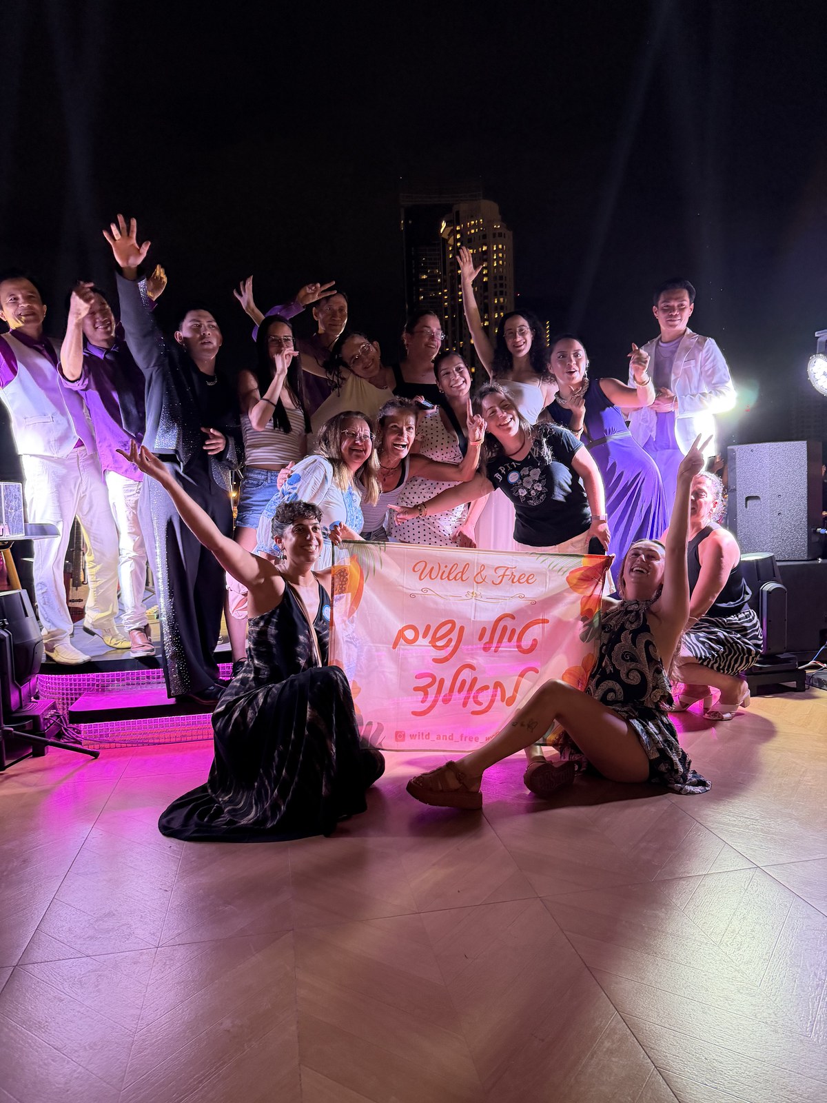 הקבוצה חוגגת בערב עם השלט של Wild & Free