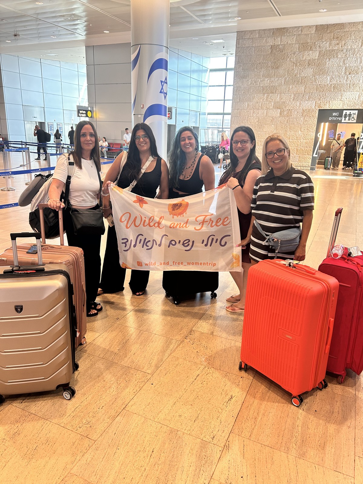 מטיילות עם מזוודות ושלט Wild & Free בשדה התעופה, לפני הטיסה